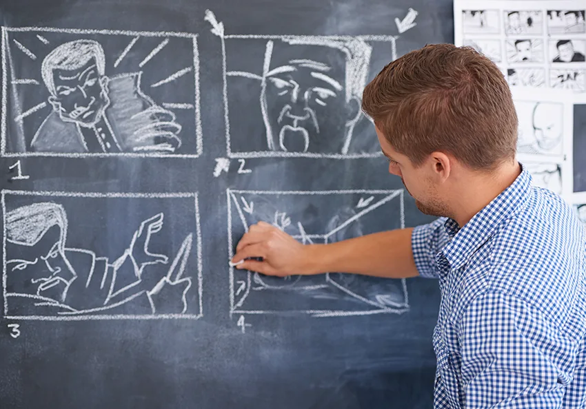 a man drawing storyboards into a chalkboard