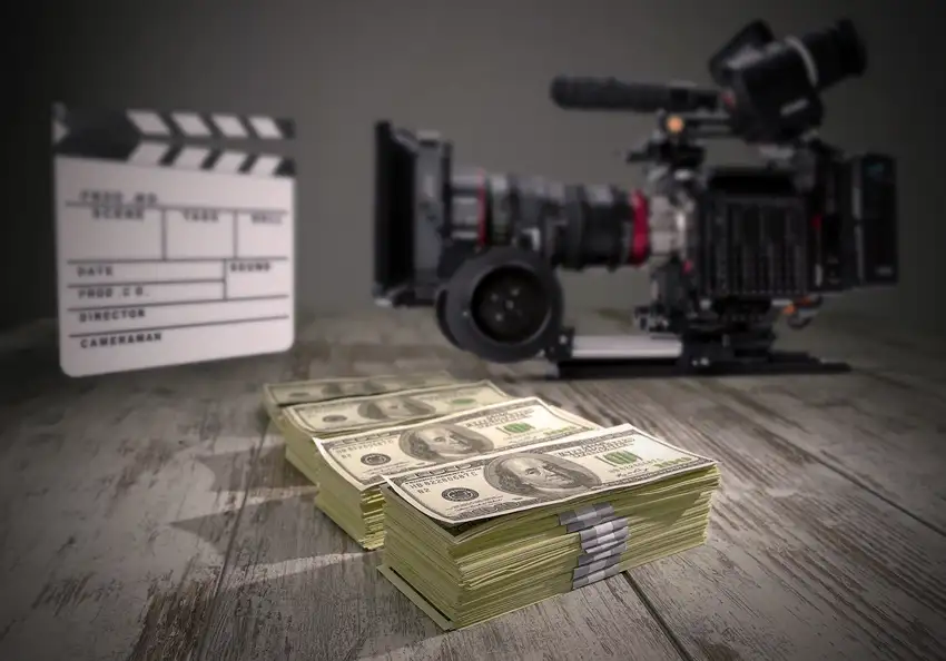 A RED cinema camera, a slate and a pile of money on a table.