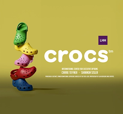 A plant, a binder and a set of Crocs shoes on a table.