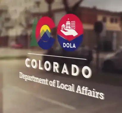 The logo of Colorado Department of Local Affairs on a glass door.
