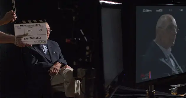 A man sits in a dark film studio ready to give an interview